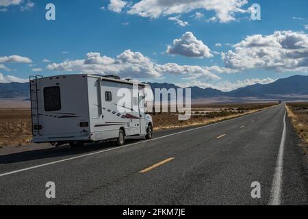 C-Typ Camper mit Slideouts stehen in der Wüste auf dem Seite der Straße mit Bergen im Hintergrund und Eine Autobahn, die vorbeiführt Stockfoto