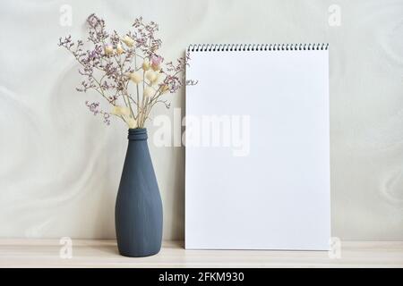 Komposition auf dem Tisch mit einer Vase getrockneten Blumen und Ein Skizzenbuch Stockfoto