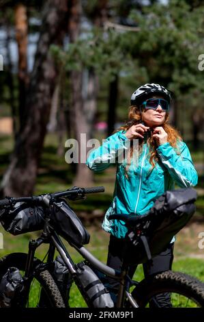 Eine Frau neben ihrem Mountainbike, die ihren Schutz befestigt Helm Stockfoto