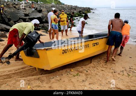 salvador, bahia, brasilien - 2. februar 2021: In der Stadt Salvador werden Fischer gesehen, wie sie ein kleines fibria-Boot auf dem Strandsand schieben. Stockfoto