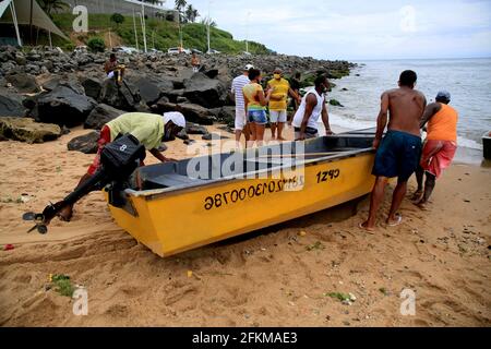 salvador, bahia, brasilien - 2. februar 2021: In der Stadt Salvador werden Fischer gesehen, wie sie ein kleines fibria-Boot auf dem Strandsand schieben. Stockfoto