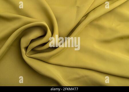 Fragment aus grünem olivfarbenem Seidengewebe. Draufsicht, flach liegend, natürlicher textiler Hintergrund und Textur. Wellenkonzept, abstrakt, spiralförmige Form. Stockfoto
