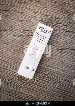 Nahaufnahme eines Corona-Schnelltests zu Hause, bei dem Sie die Ergebnisse nach 15 Minuten mit dem positiven, zweistreifigen Testergebnis erhalten, das besorgt ist, infiziert zu sein Stockfoto