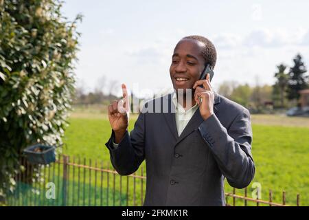 Erfolgreiche positive afroamerikanische Geschäftsmann macht einen Anruf mit Ein Kunde Stockfoto