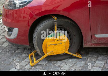 Ein Vorderrad, das durch Radsperre blockiert ist, um nicht autorisierte oder illegale Parkplätze zu erhalten. Eine Radklemme, die auch als Radmanschette oder Parkmanschette bezeichnet wird. Stockfoto