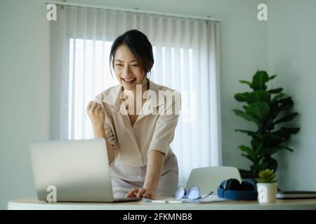 Geschäftsanfrauin war gemeinsam in einem Büro an einer Konferenz und begeisterte sich für den Erfolg auf dem Laptop-Computerbildschirm. Stockfoto