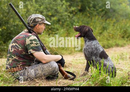 hunter mit seinem Hund während der Rast auf dem gemähten Gras Die Herbstjagd Stockfoto