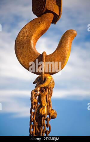 Rostiger alter Kranhaken mit Ketten, die daran hängen. Blauer Himmel Hintergrund. Stockfoto