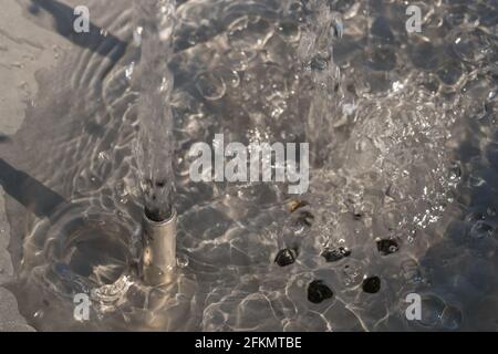 Detail eines Edelstahl-Brunnenhahnes mit vertikalem Der Wasserstrahl kommt heraus Stockfoto