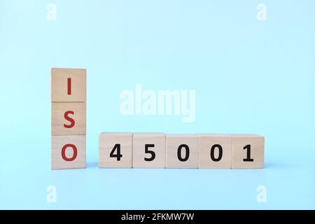 ISO 45001 oder Standardkonzept Arbeitsschutz auf Holzblöcken mit blauem Hintergrund. Stockfoto