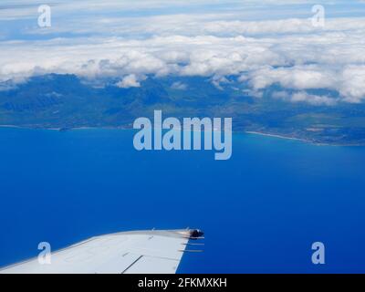 Luftaufnahme hoch vor der Küste von Makaha und Waianae mit dem Flügel eines kommerziellen Düsenflugzeugs mit Wolken über der Insel Oahu. Stockfoto