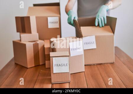 Mann verpackt Kartons mit zerbrechlichen Etiketten Stockfoto