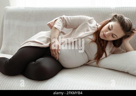 Stilvolle Schwangerin im letzten Monat ruht sich zu Hause auf dem Sofa aus. Stockfoto