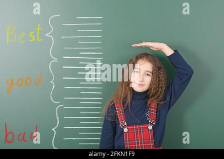 Vorpubertär Mädchen Messung ihrer Höhe auf gezeichneten Kreide Höhe Meter. Mädchen ist hinter der Schule Board Hintergrund. Hochauflösendes Foto. Volle Tiefe von Stockfoto