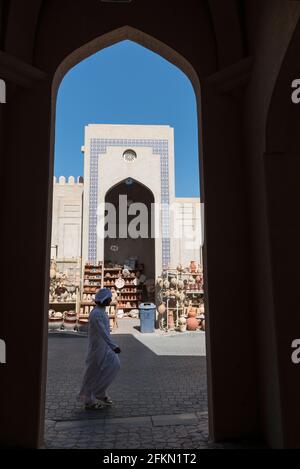 In Nizwa passiert ein Mann einen schattigen Teil einer Straße mit einer Ausstellung von Tontöpfen. Region Ad Dakhiliyah, Oman Stockfoto