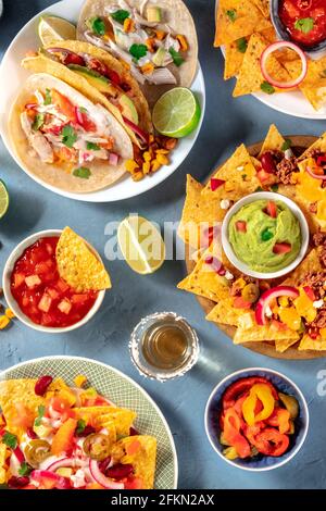 Mexikanisches Essen. Tacos, Nachos und Tequila, von oben mit einer Vielzahl von Dips und Saucen geschossen Stockfoto
