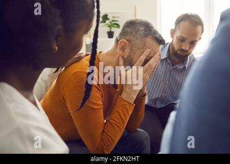 Verschiedene Menschen in der Gruppentherapie beruhigenden Mann hilft ihm zu behandeln Mit Trauer oder Lebensprobleme Stockfoto