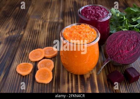 Verschiedene Gemüse-Smoothies oder Püree in den kleinen Gläsern auf dem braunen Holzhintergrund. Nahaufnahme. Stockfoto