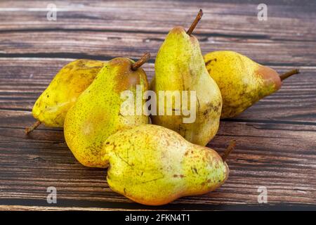 Fünf Birnen (Pyrus communis) der Sorte Conference auf einem rustikalen Holztisch. Stockfoto