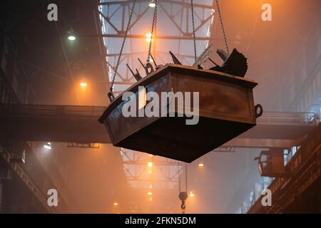 Container mit Stahlteilen auf Industriefrachtkran im metallurgischen Werk. Stockfoto