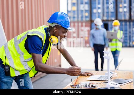African American Industrial, Factory and Energy Engineer Specialist. Portrait Black man Engineering hält Windmühle Modell Container und Solarzelle auf Stockfoto