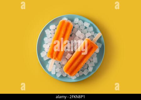 Orangefarbene Eiszapfen auf gelbem Hintergrund Stockfoto