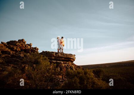Low-Angle-Ansicht von jungen Mann und Frau stehend suchen Bei schöner Aussicht nach dem Wandern stehen auf Bergklippe Gipfel Stockfoto