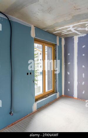 Interieur einer neuen Wohnung mit Fenstern im Bau ohne Abschluss in dunklen Tönen mit elektrischen Löchern und Verkabelung für Deckenstrahler. Hi Stockfoto