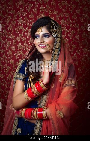 Vertikale Aufnahme einer hübschen und attraktiven indischen Frau, die posiert Mit traditioneller Brautkleidung Stockfoto