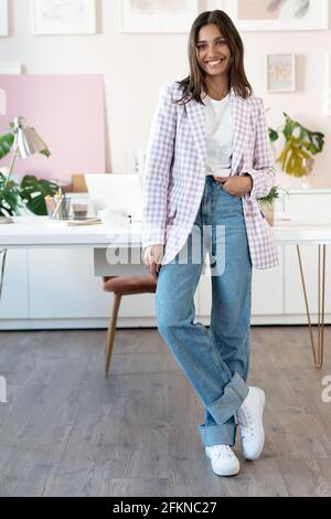 Selbstbewusste junge Frau in eleganter Freizeitkleidung lächelnd im Stehen In der Nähe ihres Arbeitsort Stockfoto
