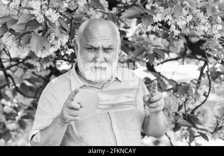 Konzept der Asthmabehandlung. Allergische Reaktion. Begrenzen Sie die Ausbreitung von Infektionen. Gesichtsmaske des älteren Mannes. Atemmaske. Pollenallergen. Mann und Blumen Stockfoto