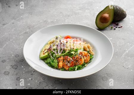 Nahaufnahme, Schüssel mit Garnelen, Quinoa und Avocado sowie Olivenöl auf grauem Steingrund. Lunch Bowl, gesunde, saubere Ernährung, Diät oder Ernährung Co Stockfoto