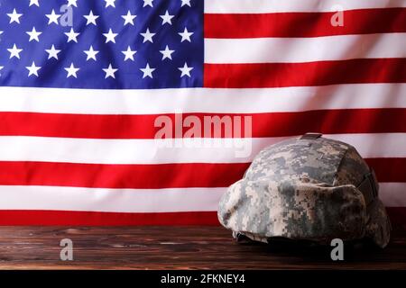 US Army Kevlar Kampfhelm, Camoabdeckung, taktische Brille, USA Flagge Hintergrund. Memorial Weekend, Veteranentag, United States of America Armed Forces Stockfoto