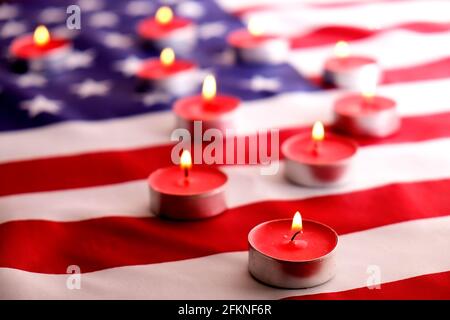 Trauerkerzen brennen auf US-amerikanischer Nationalflagge Hintergrund. Memorial Weekend, Patriot Veterans Day, 9/11 National Day of Service & Remembrance. Stockfoto