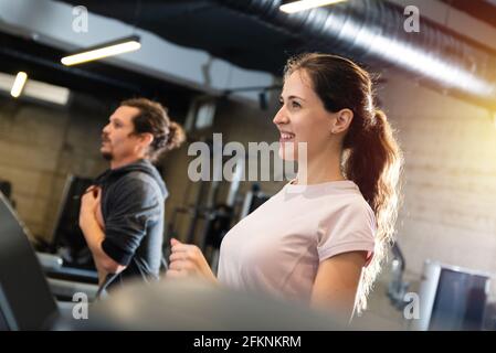 Junger Mann und schöne Smirigg Brünette Training auf dem Laufband. Stockfoto