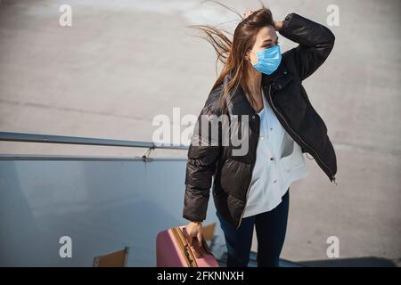 Junge weibliche Reisende an einem windigen Tag am Flughafen Stockfoto