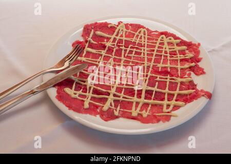 Carpaccio aus Rind mit Mayonnaise-Sauce im klassischen Cipriani-Stil Eine weiße Platte Stockfoto