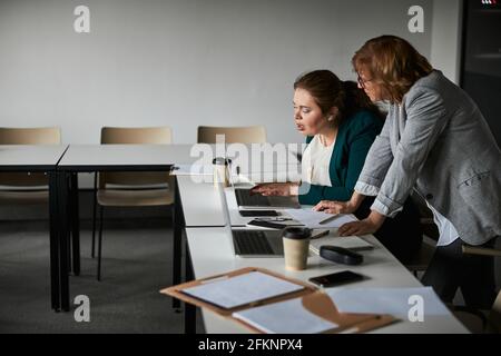 Trainee klickt unter Aufsicht des Chefs auf die Laptop-Tastatur Stockfoto