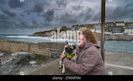 In Porthleven, Cornwall, wird eine Frau mit Hund vom Wind geblasen Stockfoto