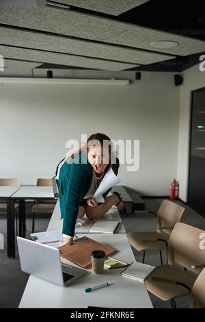 Frau, die im Büro verrückt wird und auf allen Vieren kriecht Stockfoto