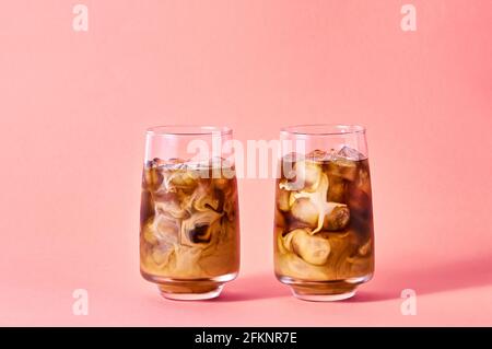 Eiskaffee mit Milch in hohen Gläsern auf rosa Hintergrund. Konzept Erfrischendes Sommergetränk. Stockfoto