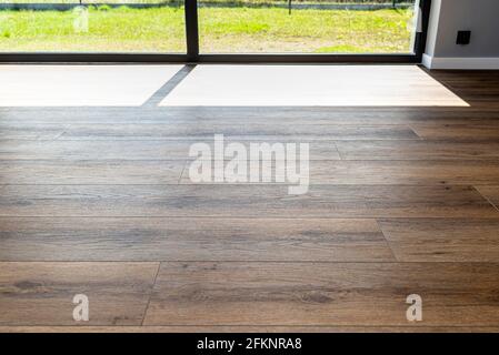 Moderne Vinylplatten imitieren Holz im Wohnzimmer mit selektivem Fokus und einem Schatten, der vom Fenster fällt. Stockfoto