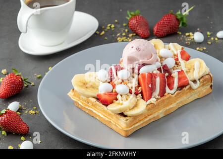 belgische Waffeln mit Erdbeere und Banane und einer Tasse Kaffee Stockfoto