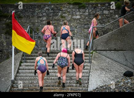 Montag, 3. Mai 2021. Langland Bay, Swansea, Wales. Eine Gruppe von Schwimmern verlässt die Strandpromenade in Langland Bay, Swansea, nachdem sie an einem nassen und windigen Montag an den Bankfeiertagen dem kühlen Meer trotzt, da schlechtes Wetter den Großteil Großbritanniens beeinflusst. Stockfoto