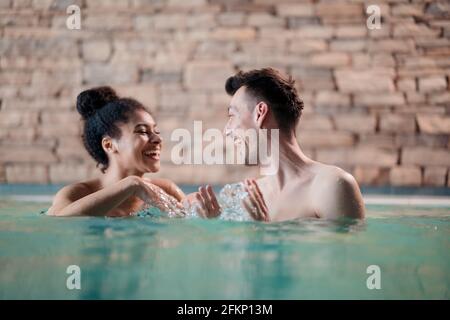 Portrait von glücklichen jungen Paar in der Liebe im Schwimmbad, reden. Stockfoto