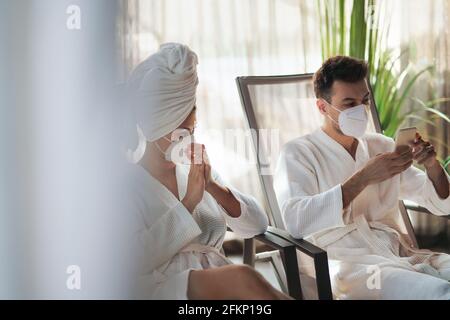Junges Paar, das im Spa-Resort sitzt und sich entspannt, Coronavirus-Konzept. Stockfoto