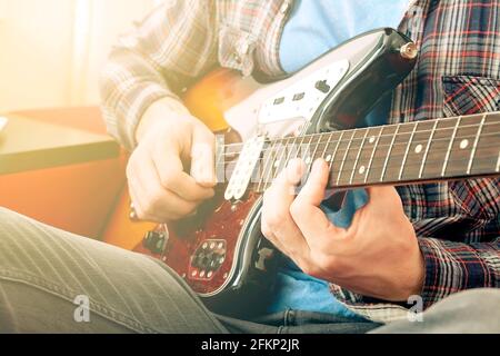 Junger Mann, Hipster-Folk-Singer-Songwriter in kariertem Kariert-Hemd, spielt Sunburst-Offset-E-Gitarre. Männlicher Gitarrist, der online Jazzmusik nimmt c Stockfoto