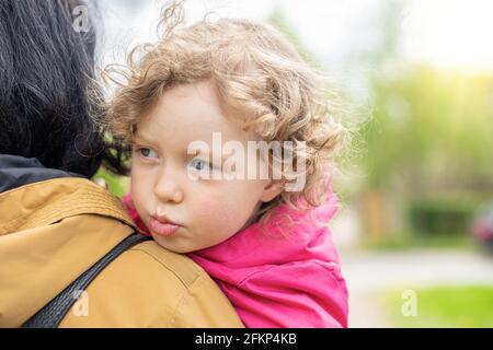 Ein trauriges Kind in den Armen ihrer Mutter. Stockfoto