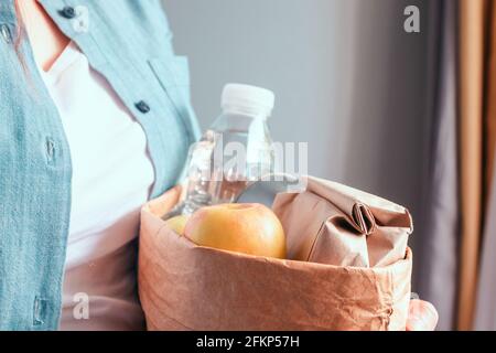 Eine Frau, die eine Spendenbox mit verschiedenen Produkten hält Grauer Hintergrund Stockfoto