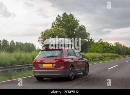 Rotes Auto mit grauem Gepäckraum auf dem Dach Straße Stockfoto